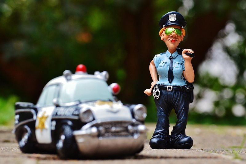 Eine Spielzeugpolizistin neben einem Spielzeug-Streifenwagen