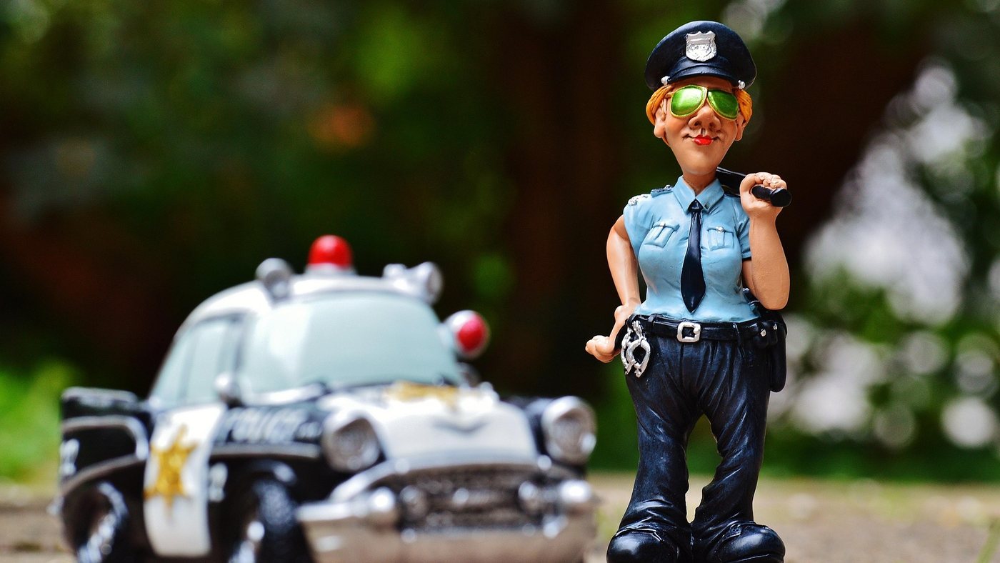 おもちゃのパトカーの横に立つ警官のフィギュア